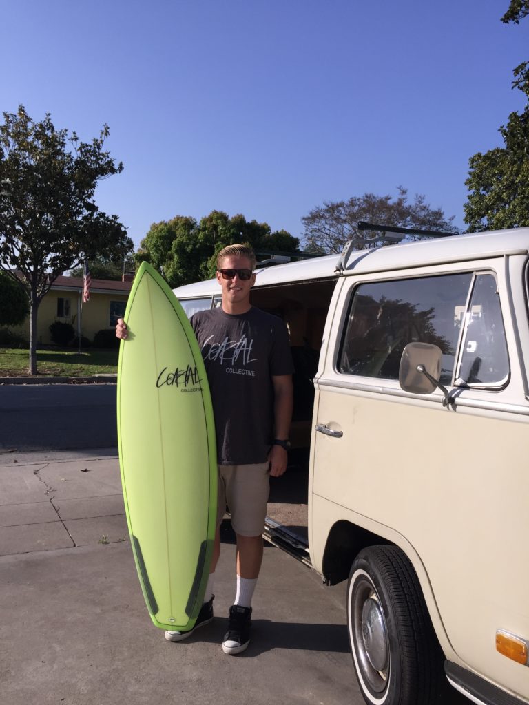 Dustin Balke, 26, poses with a Coastal Collective surfboard and T-Shirt. Photo credit: Bianca Granado
