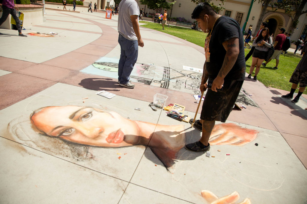 Chalk Art Contest: People category winner Andres Martinez touches up his portrait while Culture winner Stephen Tith draws to the right of him. Photo credit: Jayna Gavieres