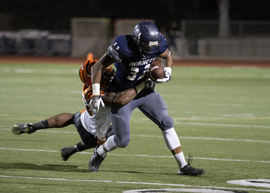 Running back Phillip Butler carries a Tigers defender multiple yards en route to a 218 yard rushing night in the Hornets victory over RCC at Shapell Stadium Saturday night. Photo credit: Chelena Gadson
