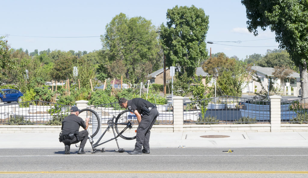 Officers inspect the bike which was involved in the accident that took place on Chapman Ave and Victoria Drive. Photo credit: Joshua Mejia