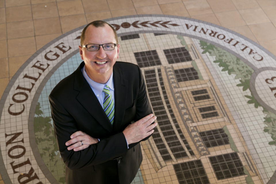 President Greg Schulz poses in front of the Fullerton College Seal. Photo credit: Fullerton College