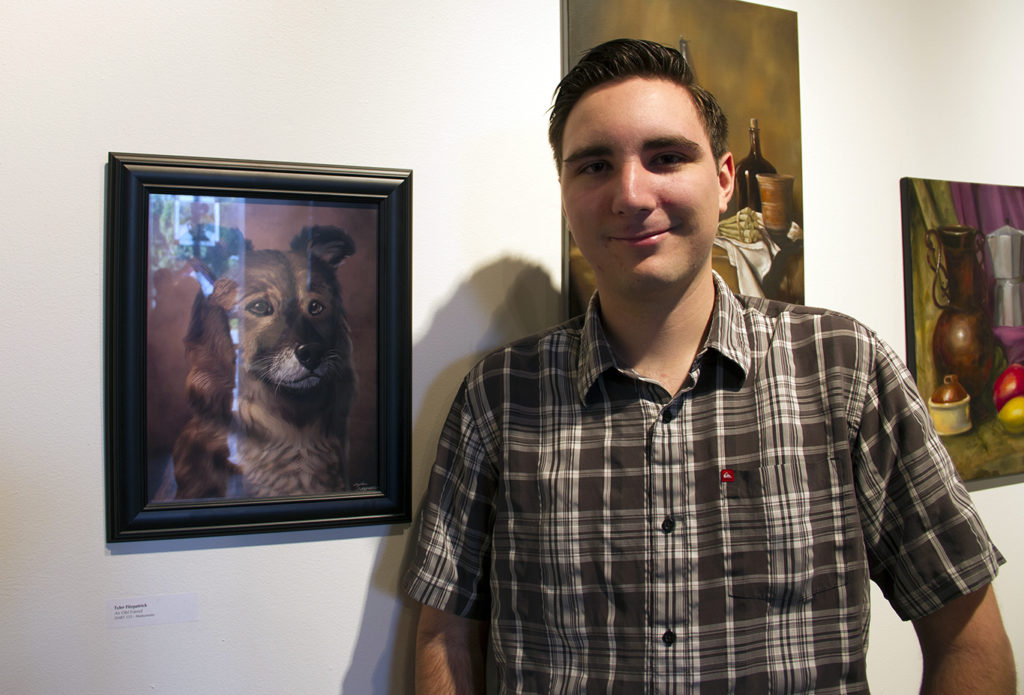 Tyler Fitzpatrick proudly standing next to his work titled An Old Friend. at the Fullerton College Gallery on Tuesday night. Photo credit: Kristine Jaranilla