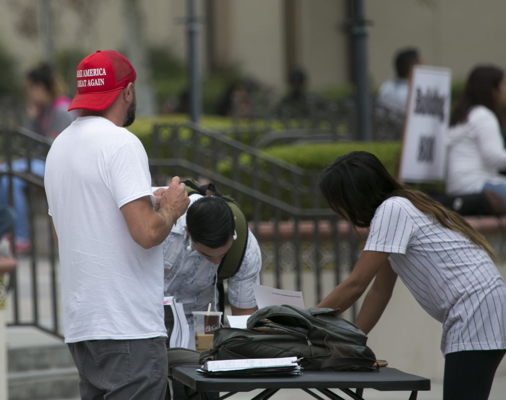 Students giving their information to a complete stranger in a red hat outside the library on Tues., Sept. 20. Photo credit: Christian Mesaros