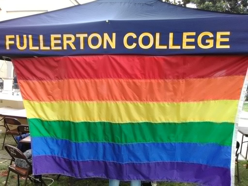 LGBTQ+ Pride Flag on display behind the Queer People of Color table on the quad. Photo credit: Frank Tristan
