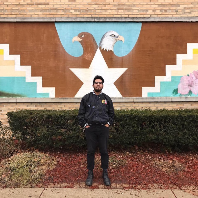 Photographer William Camargo posing in front of a mural. Photo credit: Edgar Baca