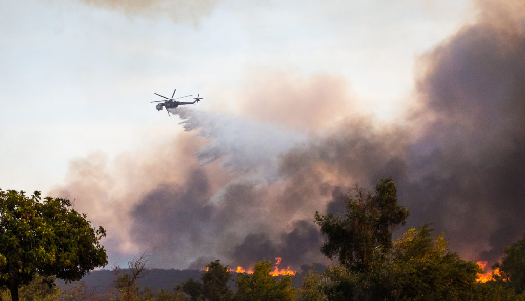 As homes are consumed by flames helicopters dowse the area in an effort to help the fire fighters on the ground during the Canyon Fire. Photo credit: Christian Fletcher
