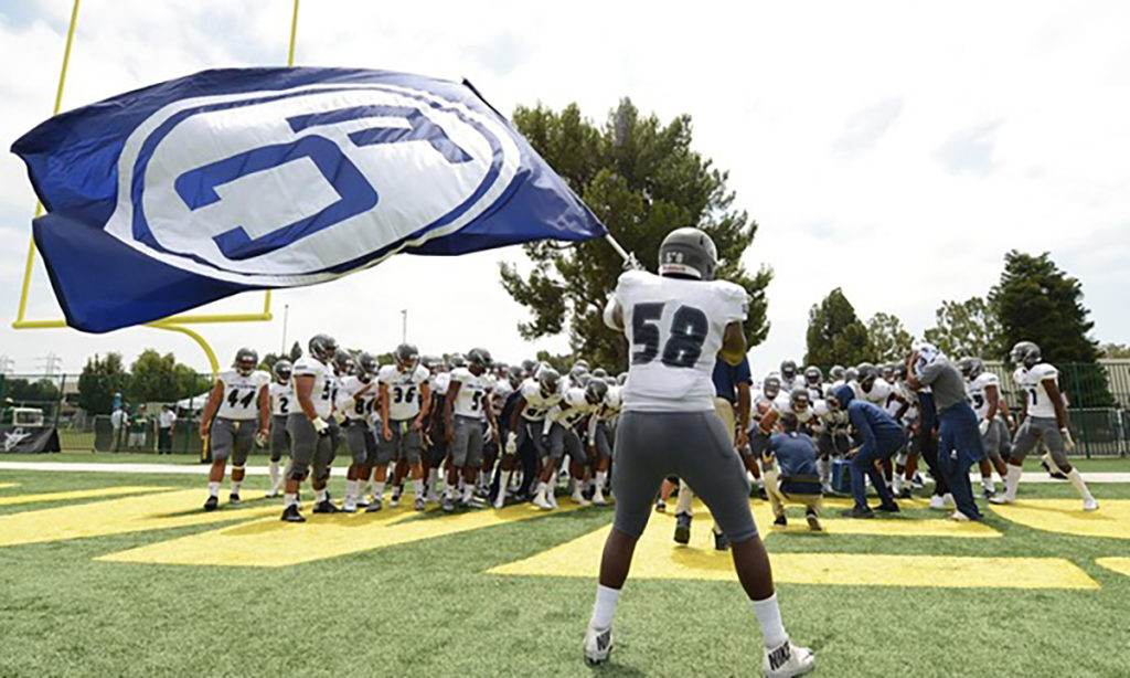 Hornets Sophomore Andrew Glover waves the Fullerton College flag before taking the field against the Tigers at Riverside City College Saturday, Sept. 8. Photo credit: Fullerton College Administration