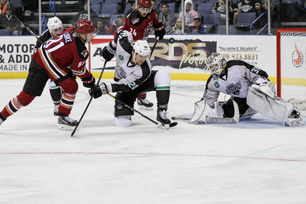Veteran Reign defenseman - Kurtis MacDermid, sprawls out in front of the net to keep Tucson right winger - Jens Looke, from becoming a dangerous option in front of the net