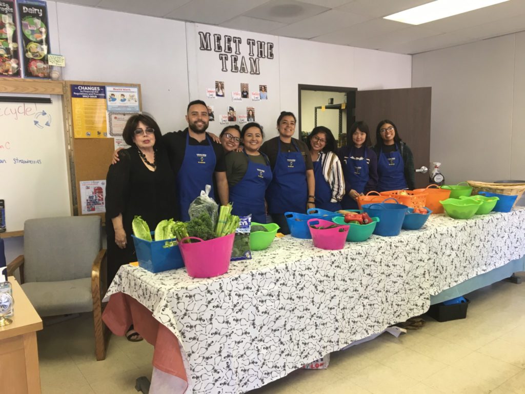 (From left to right) Adela Lopez, Miles Aiello, Nallely Almanza, Veronica Almanza, Laura D. Sanchez, Sinmier Sanchez, Ru-yi Ou Yang (Susie), and Isabel Medina are volunteers helping to give students whatever they would like to take home. Photo credit: Jazlyn Morales