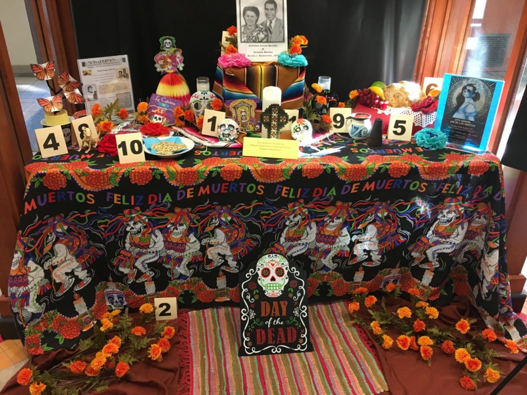 The Cadena Cultural Centers ofrenda gives students an idea of how they may want to decorate their own. Some popular items are marigold, skull sugar cubes, photos, and food. Photo credit: Ayanna Banks
