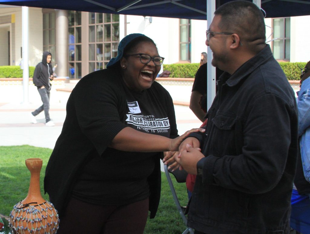 Laughs are shared at the Umoja booth between a student and representative in March 2019.