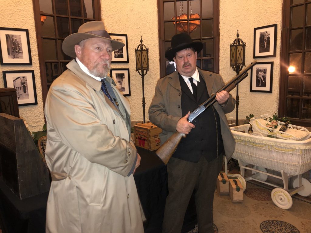 Two Prohibition agents stand in front of confiscated bottles of alcohol. John Olinger is seen to the left and Bruce Willis is on the right. Photo credit: Holly Hulion