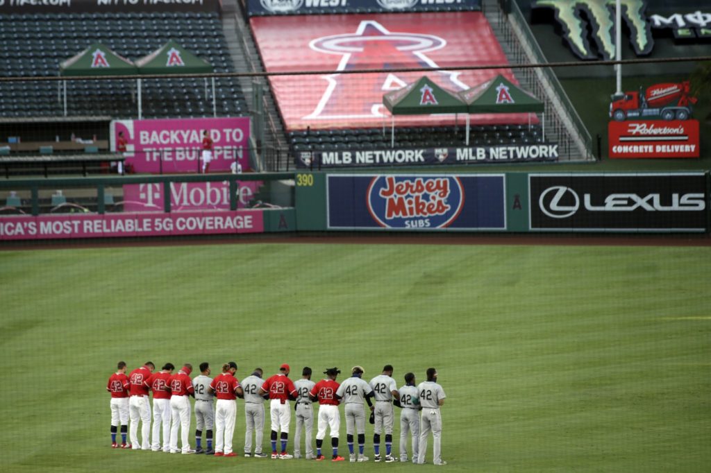 Players from the Los Angeles Angels and the Seattle Mariners, all wearing No. 42 for Jackie Robinson Day, stand during the national anthem prior to a baseball game in Anaheim, Calif., Friday, Aug. 28, 2020. Photo credit: AP Photo/Alex Gallardo