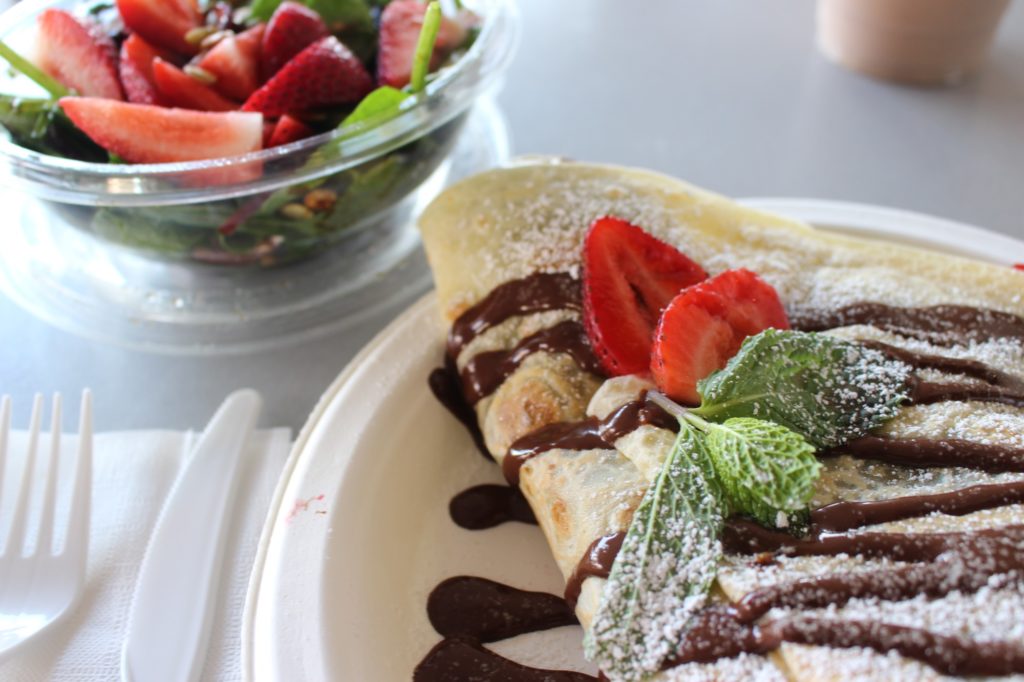 The crepe is beautifully plated and garnished with fresh strawberries, mint, and powdered sugar. Photo credit: Myron Caringal