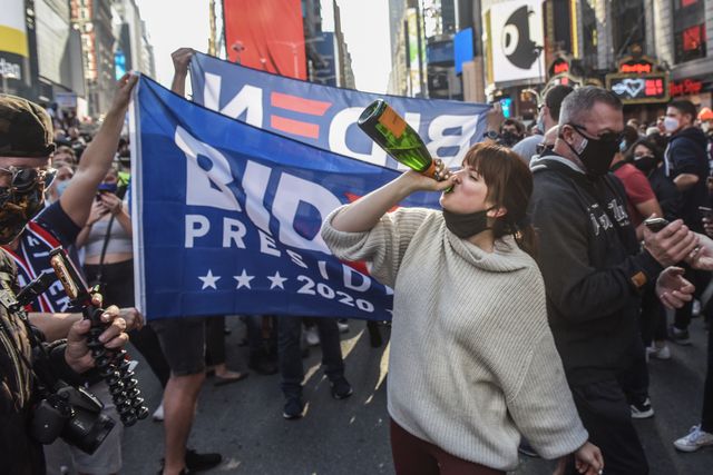 Person drinking Champaign with Biden and Harris flag in the background Photo credit: Stephanie Keith & esquire
