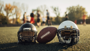 American football helmets and ball on the playing field. Photo credit: Getty Images & South_agency