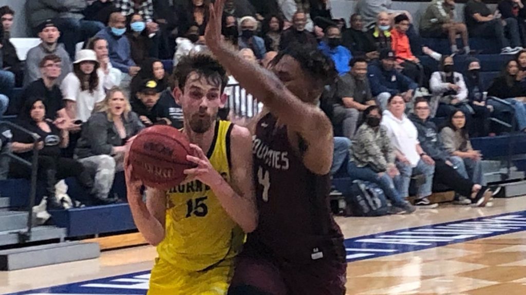 IMAGE: Two mens basketball players on the court during a game. Hornets guard Ronnie Stapp drives to the basket for two of his 19 points on Thursday night.