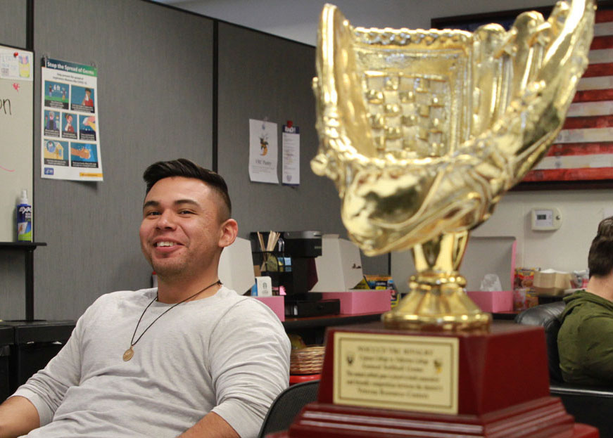 A student at the Nov. 9 Veterans Appreciation Luncheon poses alongside a trophy commemorating the Fullerton College VRCs recent win in a softball game against the Cypress College VRC. Photo credit: Julianne Le
