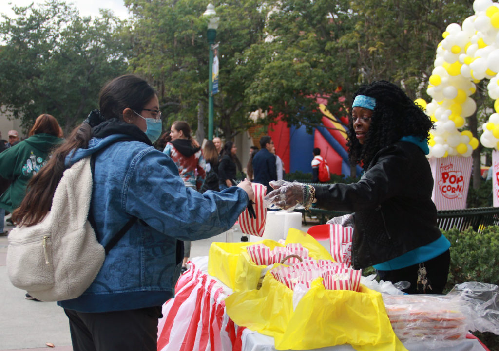 Student Life and Leadership worker Les-Sie Crockrom hands out free popcorn in the Fullerton College Quad on Dec. 1, 2022. Anyone who received a ticket after checking in could pick up a bag of popcorn. Photo credit: Jasmyn Ramirez