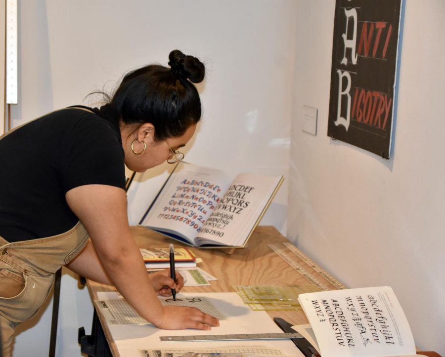 Gabriela Castillo, sophomore painting major, draws in the interactive space in the calligraphy exhibit.