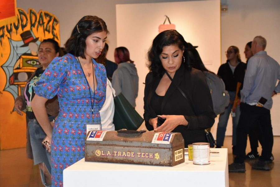 Syanne Mendoza, sophomore art history major, and Jesseca Mendoza appreciating "Cassius Clay" enamel and mixed media on toolbox by Nat Isobaker (backside with "L.A. Trade Tech" is showing).