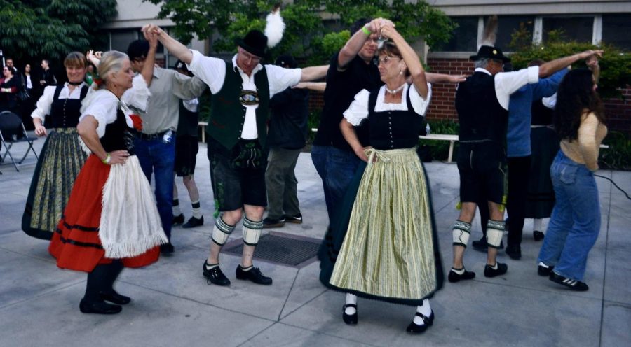 The Schuhplattler dancing troupe teaches audience volunteers German and Bavarian dances at the German Cultural and Film event at Fullerton College, Wednesday, April 19, 2023. Christine Garner, in red skirt, dances with German professor Klaus Hornell.
