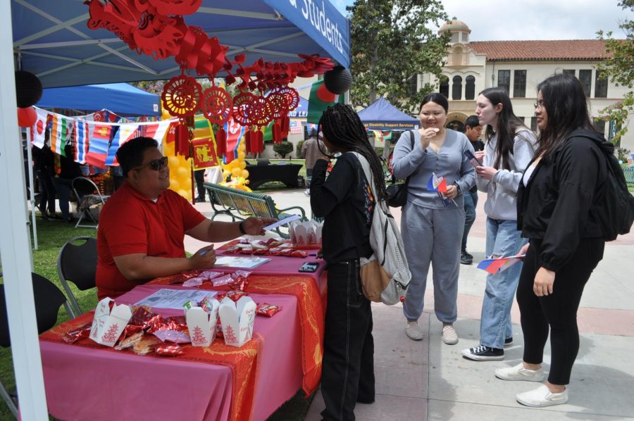 Veterans Resource Center Coordinator and Advisor to Alpha Gamma Sigma Honors Society, Marwin Luminarias greets visitors to the APIDA event, Monday, May 1, 2023 Fullerton College at the Chinese booth, with free Choco pies and seaweed-flavor treats Photo credit: Dana Rose Crystal