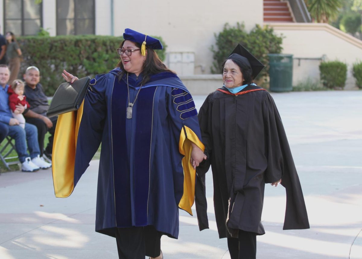 Fullerton College president Cynthia Olivo assists Dolores Huerta as they walk back from the stage at Olivos Investiture ceremony on Friday, Sept. 29, 2023.