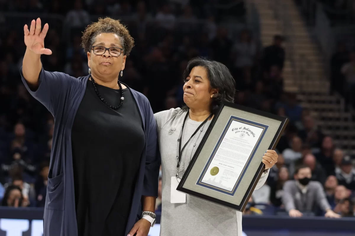 Marcia Foster (left) receives an honorary certificate from Deputy Mayor Judith Thomas (right) that formally announces Feb. 12th as Hank Foster Day in Indianapolis. Foster waves to the home crowd of a Butler basketball game where they face Marquette. Feb. 12th, 2022.