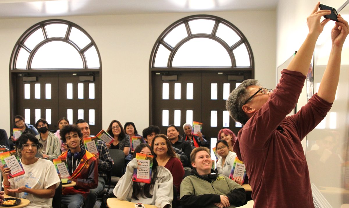 After reading excerpts of Everything I Learned, I Learned in a Chinese Restaurant, author and filmmaker Curtis Chin holds his phone up to take a selfie of everyone that received a copy of his memoir in the Humanities Building on Wednesday, Feb. 14 at Fullerton College.
