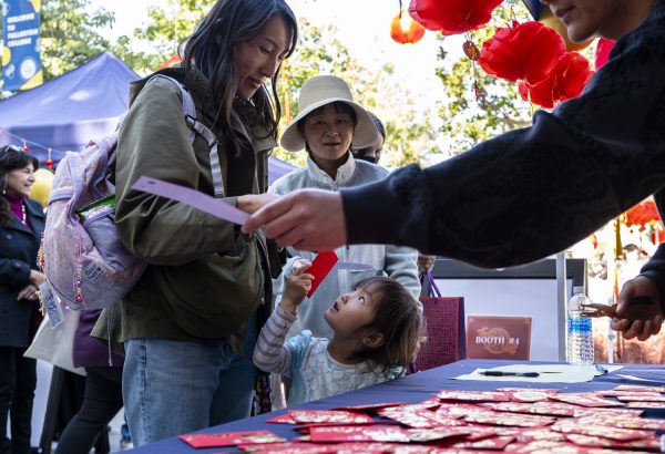 Holding a red envelope, a young girl looks up at her mother, Tomone Nakashima.  The mom and daughter pair had just been released from a session of North Orange Continuing Educations Mommy and Me parenting program.  Originating in China, red envelopes are traditionally given as gifts at special occasions such as birthdays, weddings and holidays.