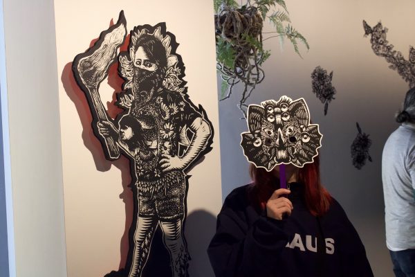 Hidden behind a mask, printmaking major Sara Rovira attends Pavel Acevedos exhibition In Spring We Are Reborn/ Renaceremos En Cada Primavera on Thursday, Feb. 15.