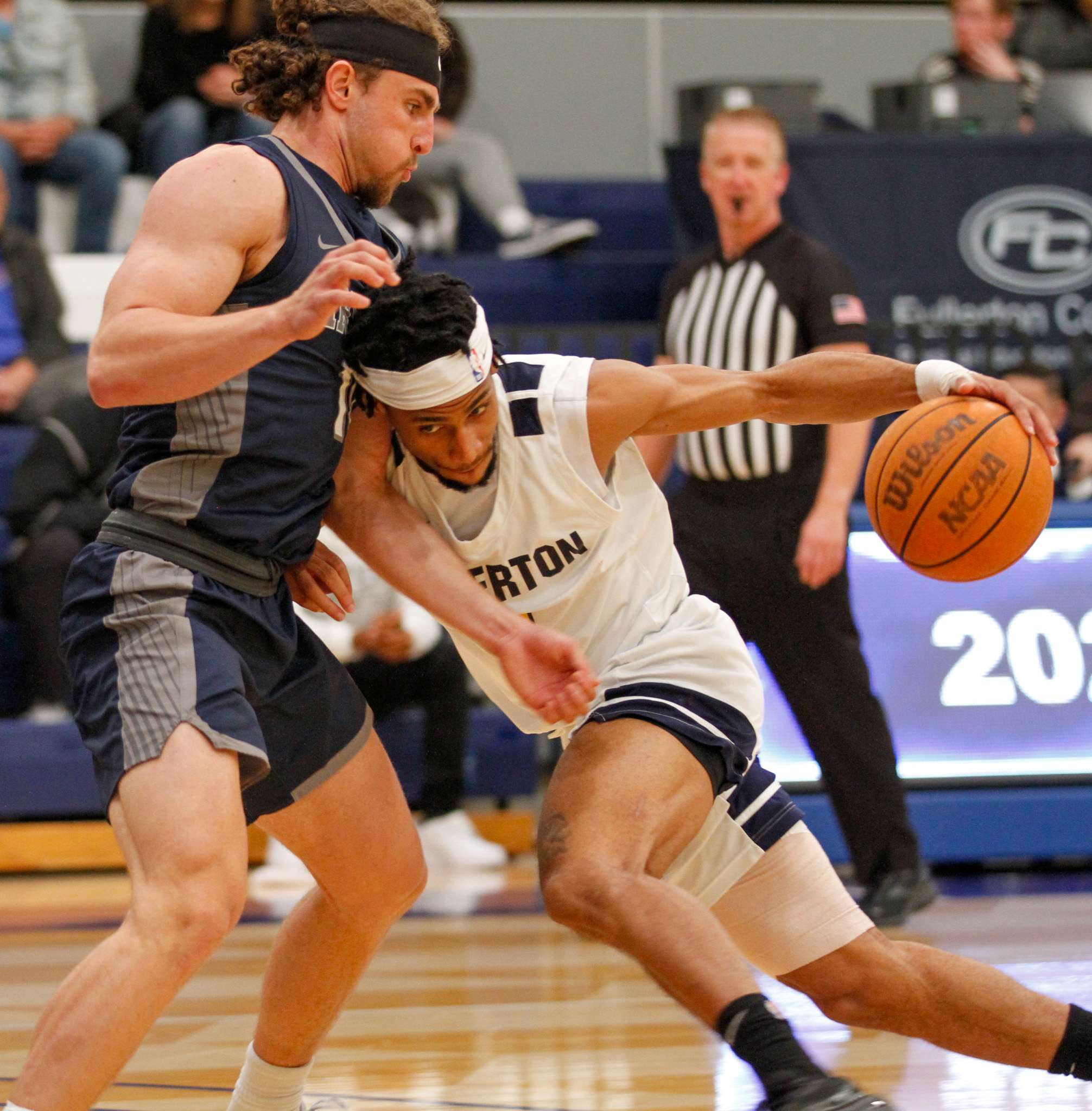 Fullerton sophomore guard Jaden Byers looks to create space by driving into Irvine freshman guard Ammon Allan on Feb. 13, 2024.
