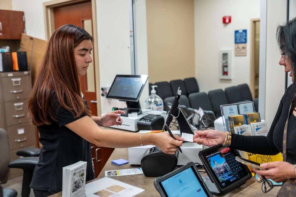 Second-year cosmetology student Lizbeth Escamilla welcomes in clients at the reception desk located in room 712-A on Friday September 6, 2024.  Appointments reminder cards are giving to clients for future appointments. 