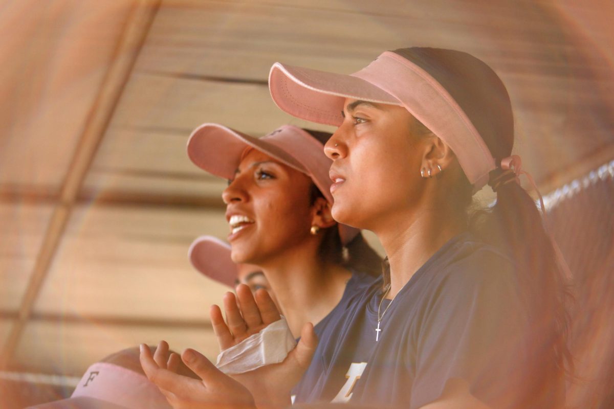 Angelina Granada and Jianna Lopez cheering on their teammates from the dugout. 