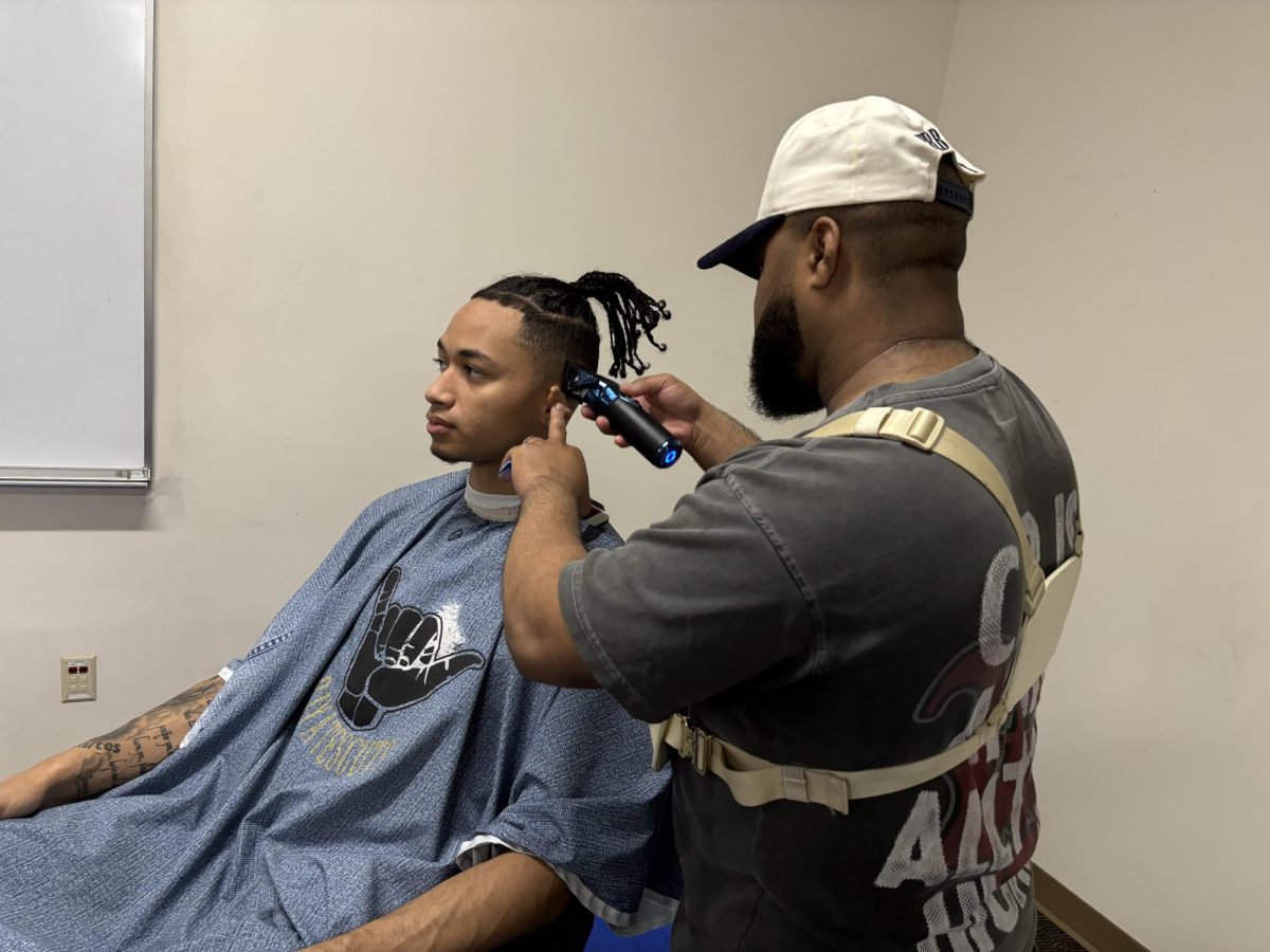 Barber PJ Yates gives student JQ Strong a haircut on Dec. 4, 2024.