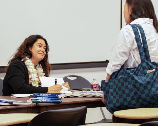 Brandy Nālani McDougall signs her book for one of the students at the Open Mic and Book Talk hosted by the APIDA Amplified Program on Oct. 8, 2025, in Fullerton, Calif.
