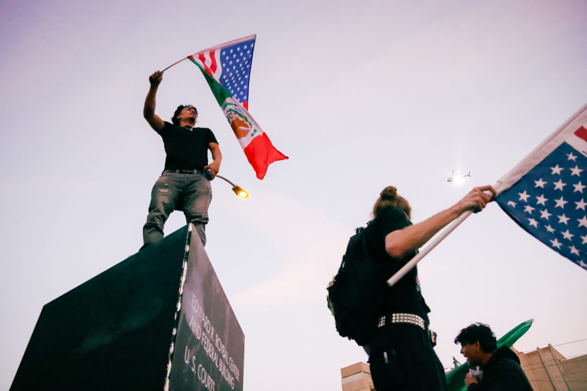 Protesters at the Metropolitan Detention Center look on behind them at a helicopter shining a searchlight down into the crowd on Jan. 30, 2026.
