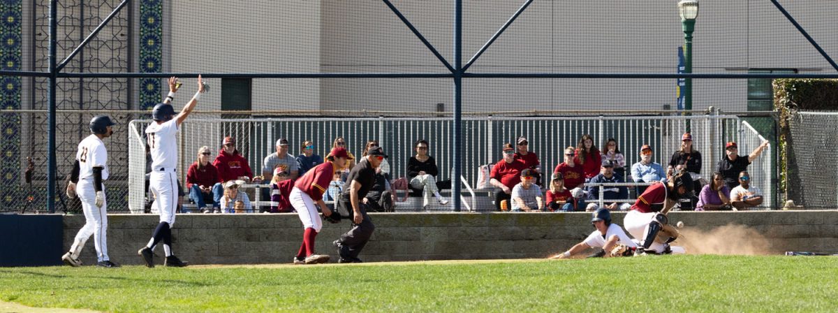 Fullerton second baseman Clint Dodson slides into home as Diego Vasquez (left) and Vinny Hudson celebrate the run.