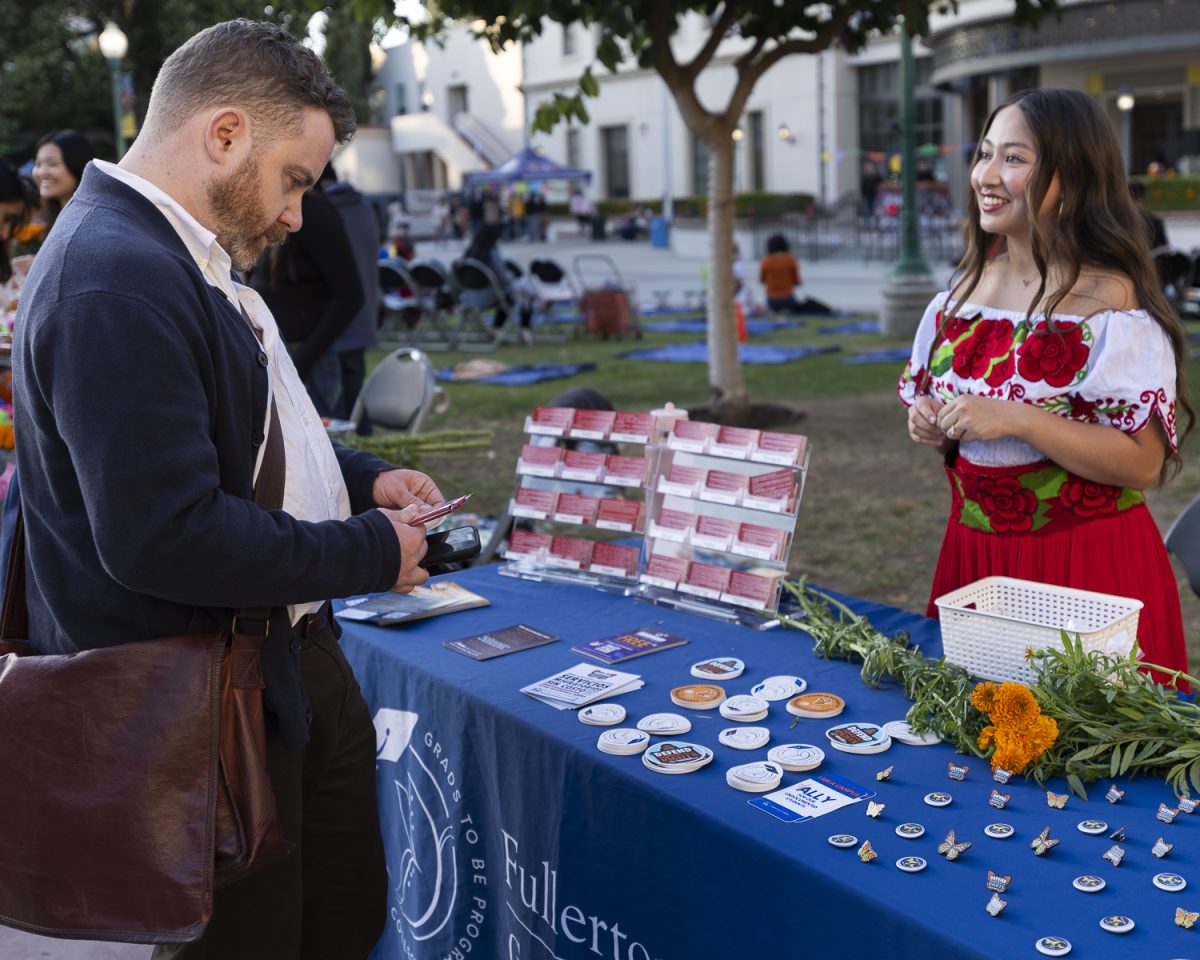 Alexander Scott (left) visits the Grads2Be information table at a Dia de los Muertos Celebration at Fullerton College.