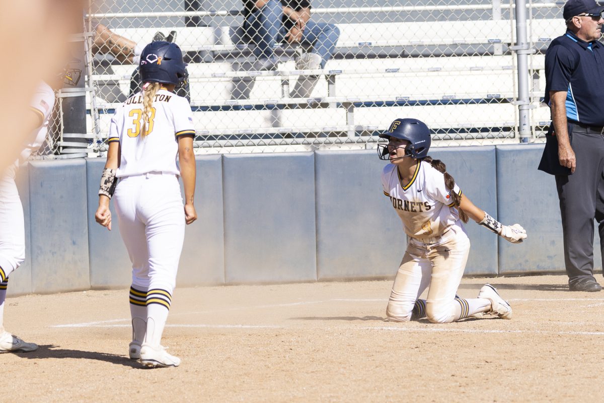 Alana Eisel (right) of Fullerton slides into home plate and celebrates toward her teammates after scoring a run in the fourth inning against Golden West on April 14, 2026, at Hornet Softball Field in Fullerton, Calif.