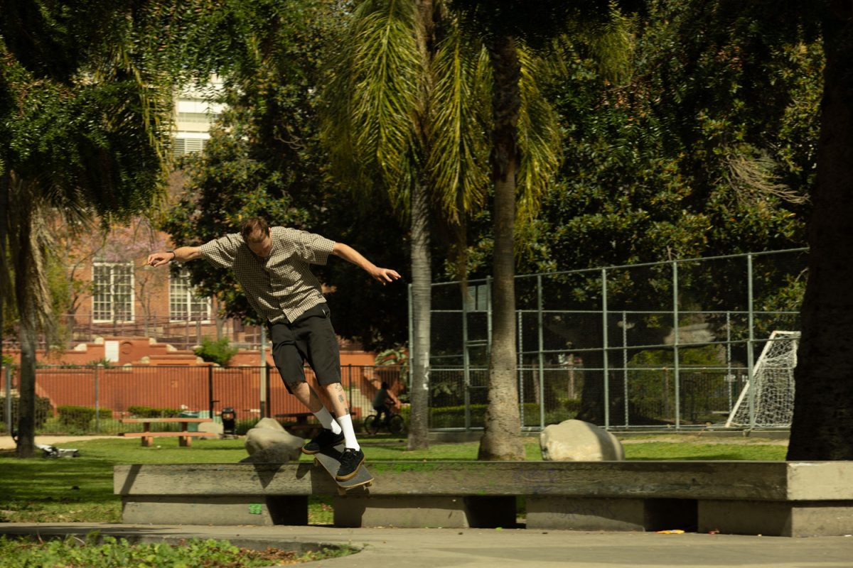 Skater in downton Los Angeles grinding on a curb at a local park.