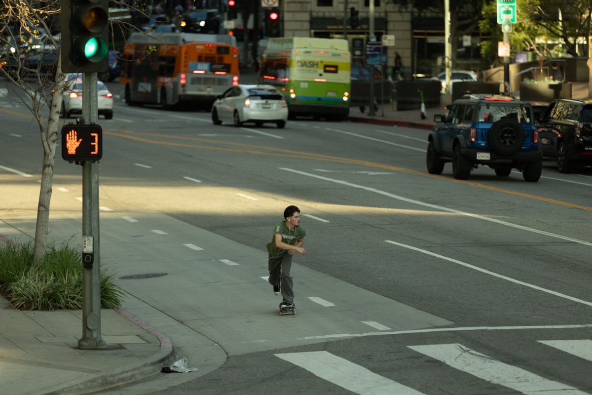 Lincoln Gonzalez riding his board down a street in downtown Los Angeles.