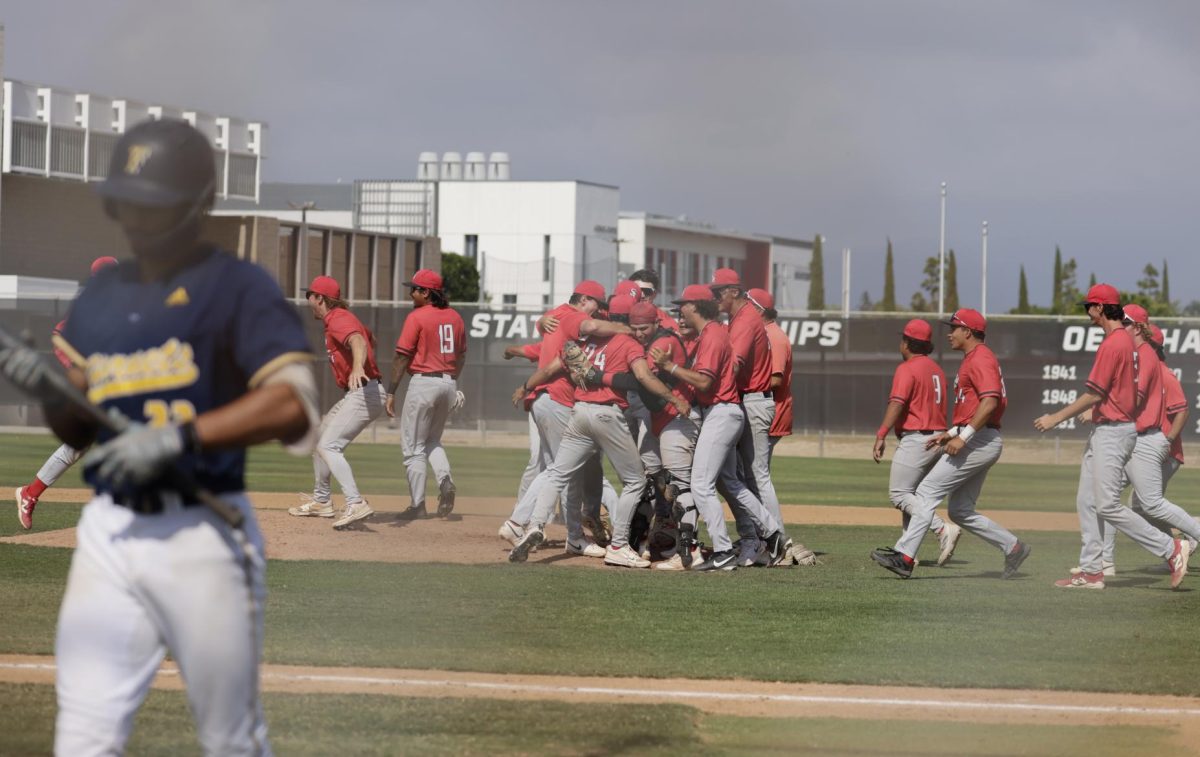 Fullerton shortstop Diego Vazquez walks back to the dugout after striking out to end the game, as the Don's celebrate in the background after winning the series on May 16 at Don Sneddon Field in Santa Ana, Calif.