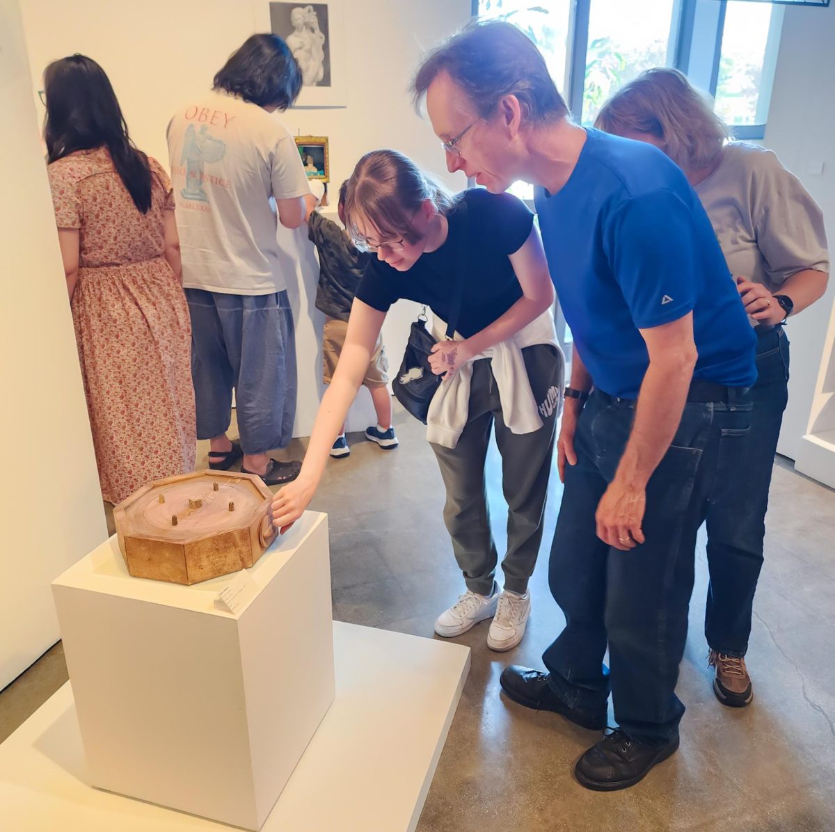 An attendee opens and closes the drawer on Henry Johnson's wood acrylic piece called "Dante's Journey" at Fullerton College on May 7, 2026.