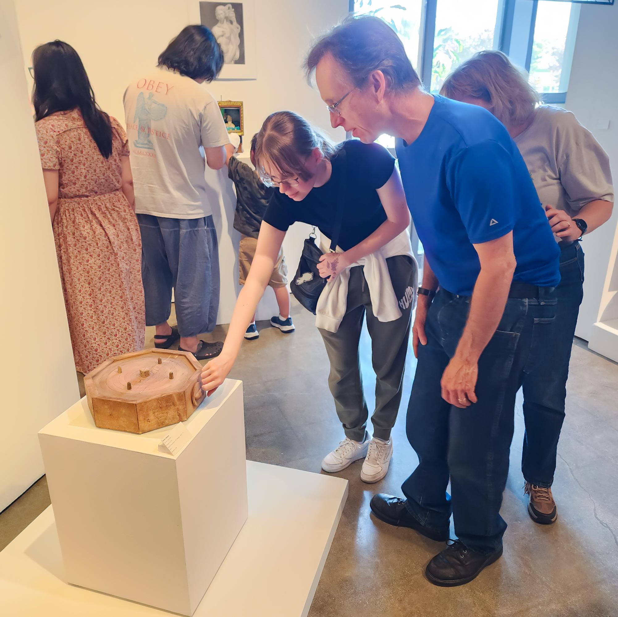 An attendee opens and closes the drawer on Henry Johnson's wood acrylic piece called "Dante's Journey" at Fullerton College on May 7, 2026.